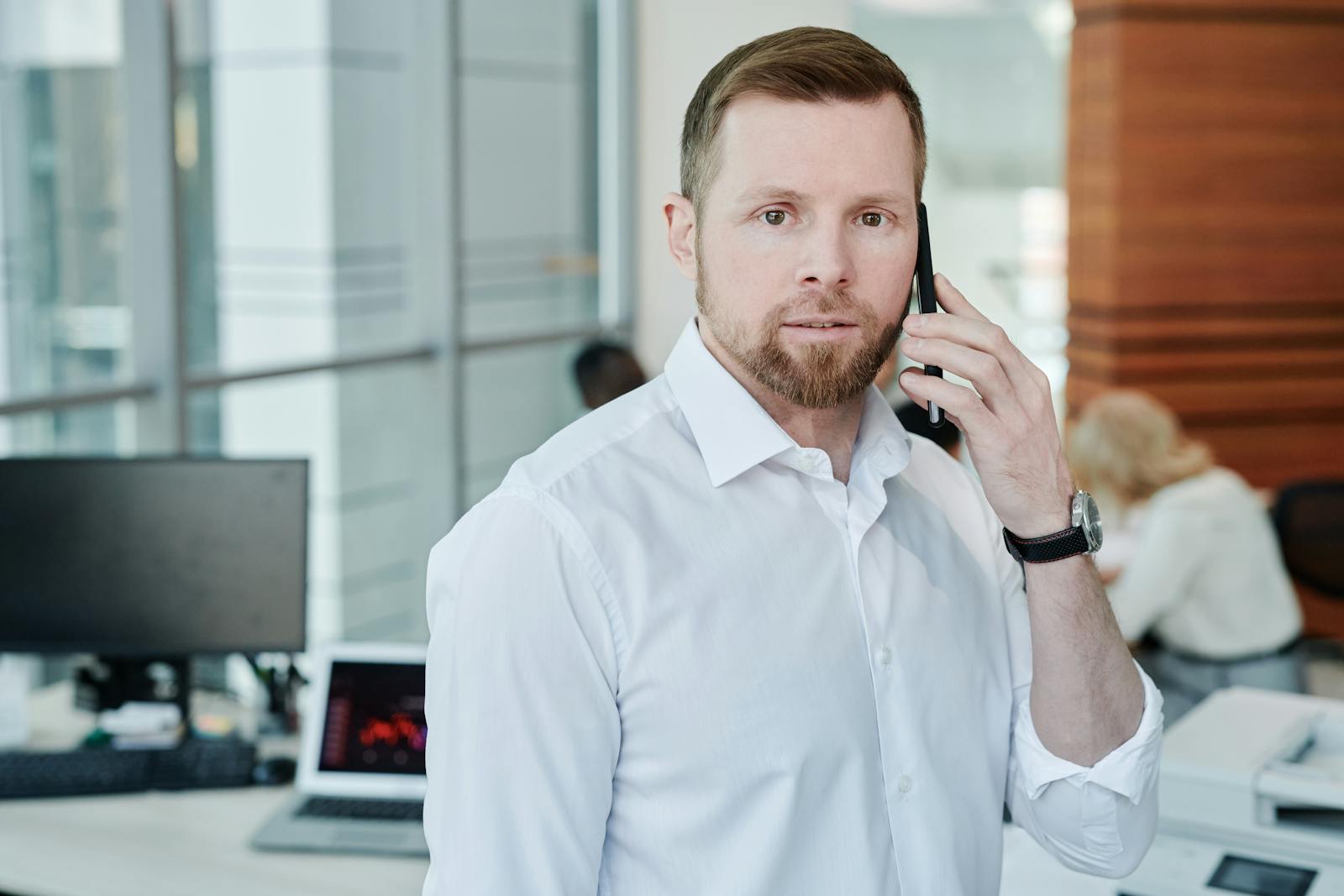 Professional man in office environment taking a business phone call.